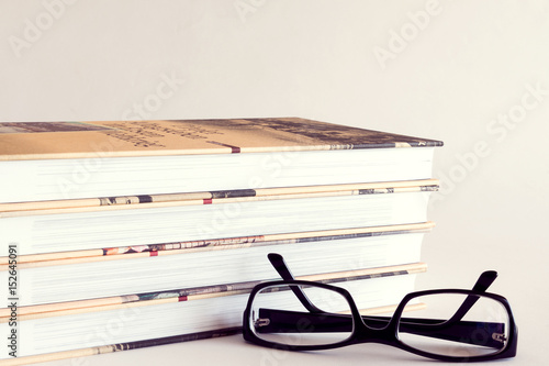 A pile of books with reading glasses