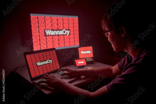 Young Asian male frustrated and confused by WannaCry ransomware attack on desktop screen, notebook and smartphone, cyber attack internet security concept photo