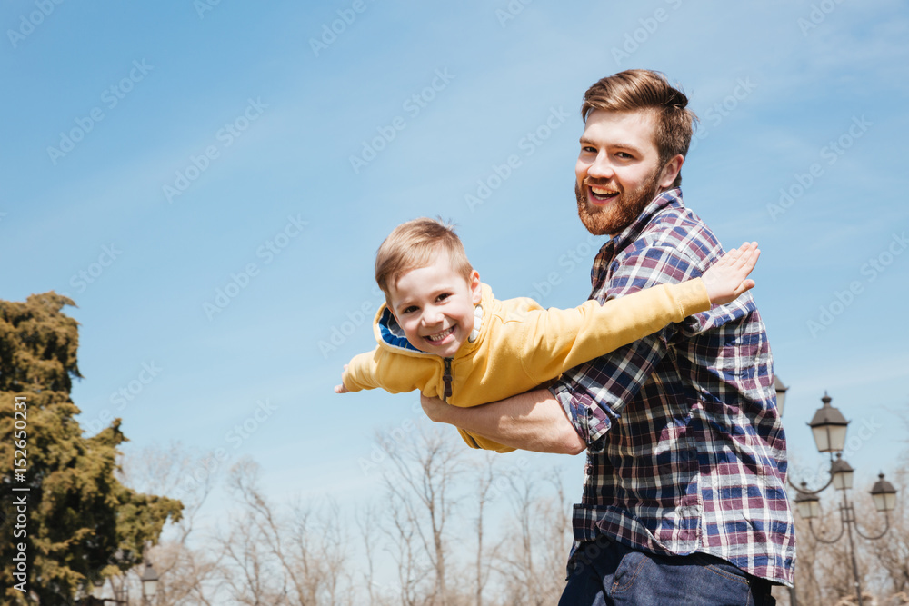 Cheerful bearded father having fun with his little son