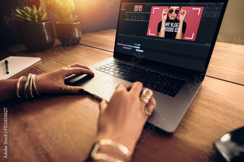 Young female vlogger editing her vlog on computer. photo