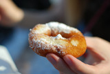 Female hands touching  dusted with powdered sugar fried donut close up.