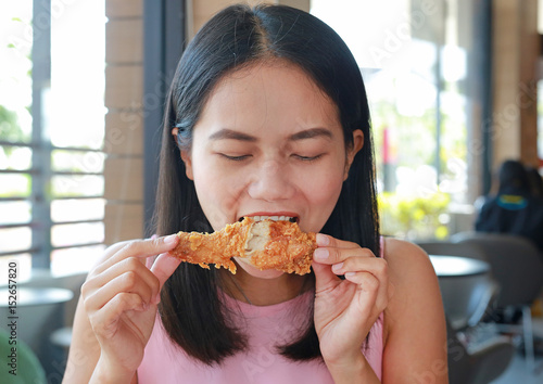 Cuadro en lienzo Close up of young asian woman eating fried chicken in cafe.