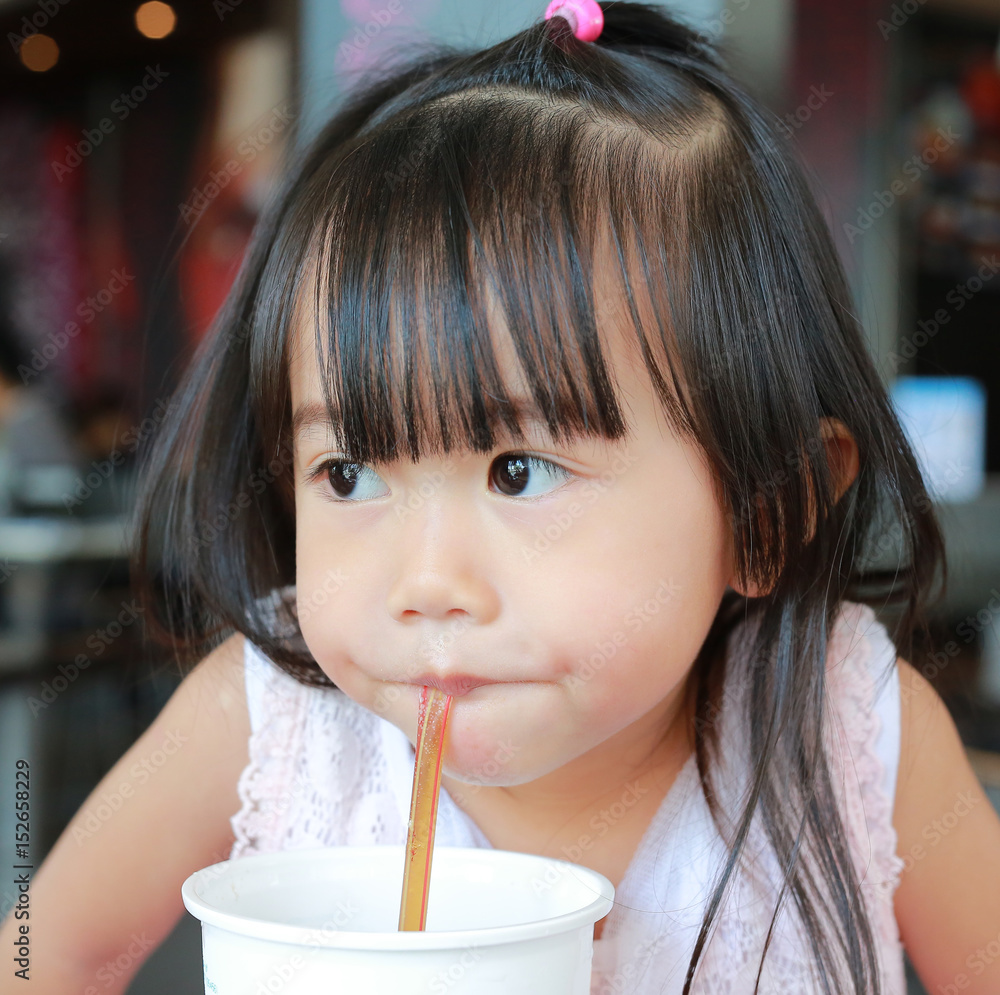 Cute little girl using straw to drink honeydew from plastic cup in cafe. Cute little girl using straw to drink honeydew from plastic cup in cafe.