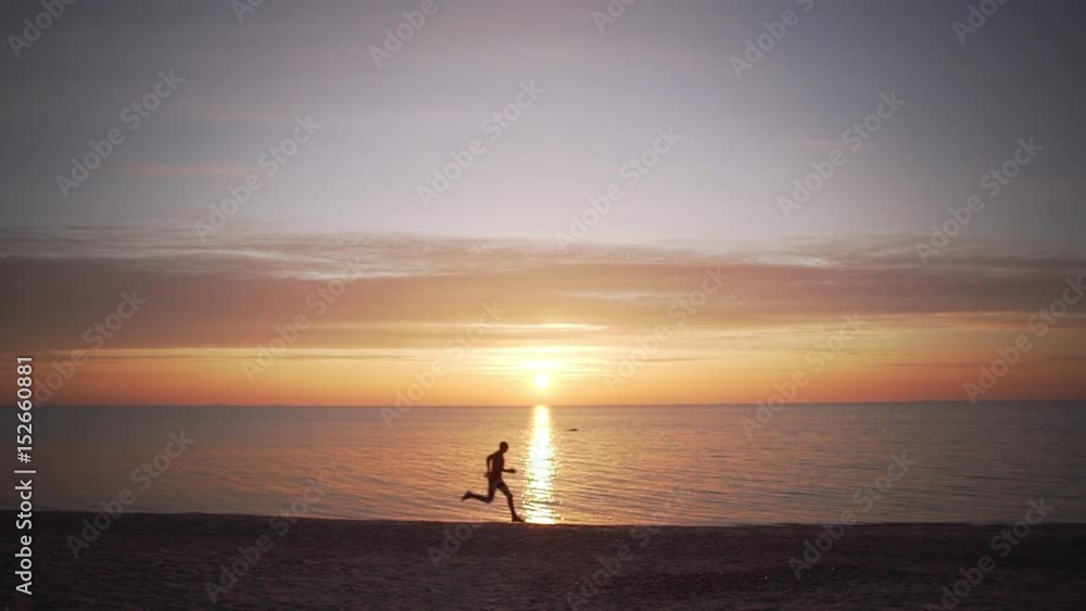 Silhouette of running man on seashore. Sun is rising from sea in slowmotion Silhouette of running man on seashore. Sun is rising from sea in slowmotion