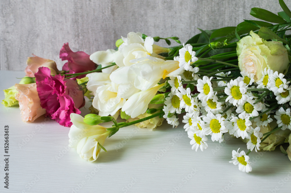 A bouquet of white freesia, lisianthus, chrysanthemum and roses.