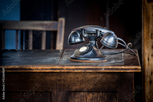 Old 1930s telephone on old wooden desk.