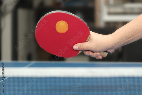 фотографія Held forehand counterhit orange table tennis ball near net on blue board