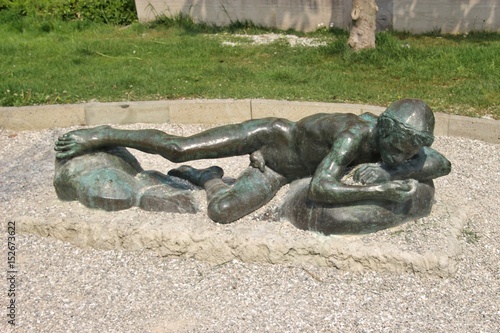 Fotografija Bronze sculpture of lying youngling in a public park in Chioggia, North Italy, Europe