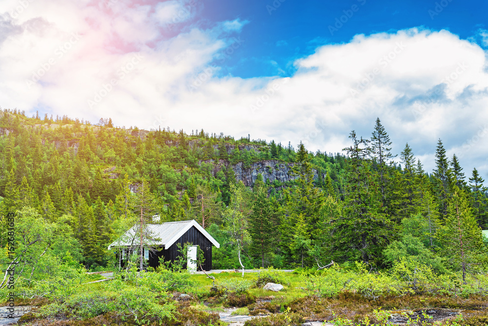 Traditional norwegian wooden house standing at the lakeside and mountains in the distance Traditional norwegian wooden house standing at the lakeside and mountains in the distance