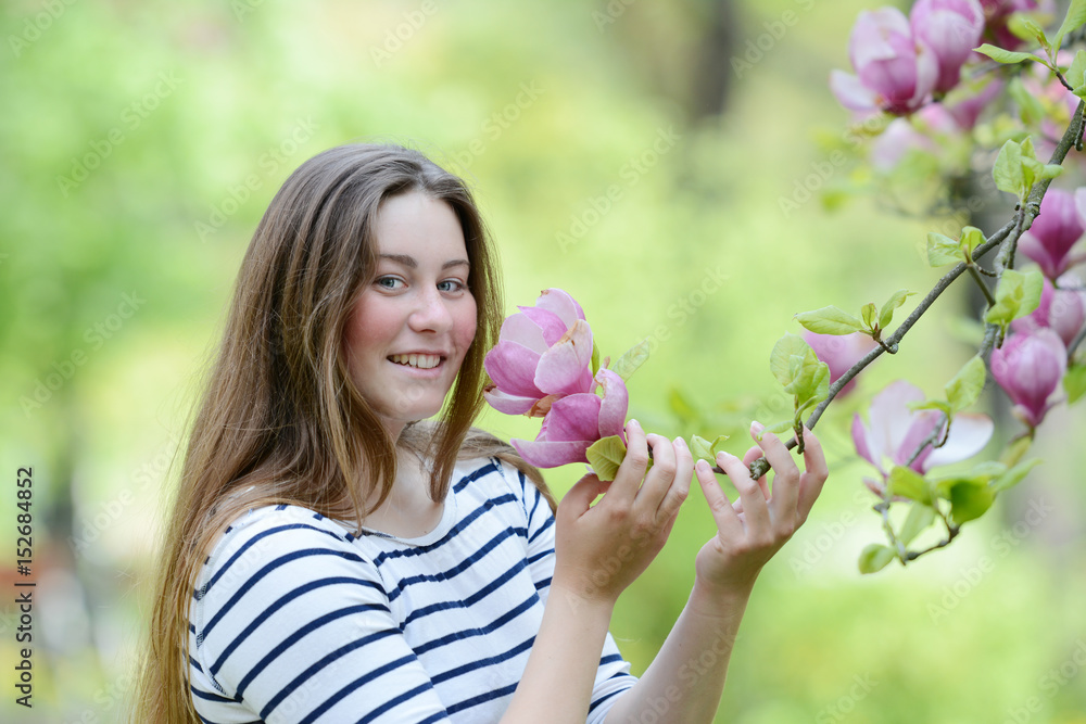 Beautiful young woman with magnolia in the park. Beautiful young woman with magnolia in the park.