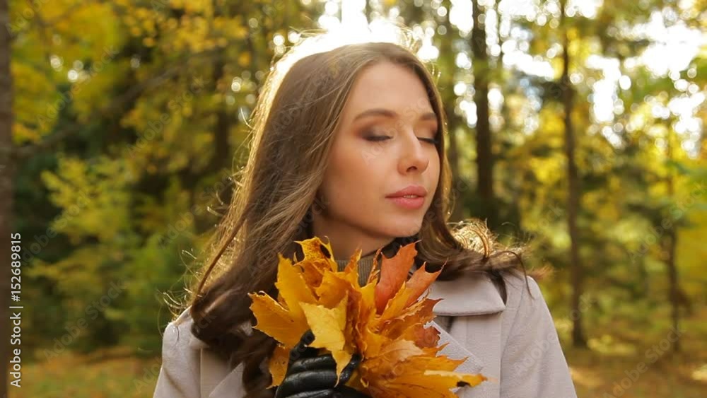 Smiling girl, full of desire, with a bunch of yellow leaves, waits for her sweetheart in a park Smiling girl, full of desire, with a bunch of yellow leaves, waits for her sweetheart in a park