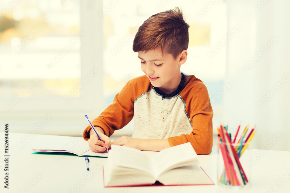 smiling student boy writing to notebook at home smiling student boy writing to notebook at home