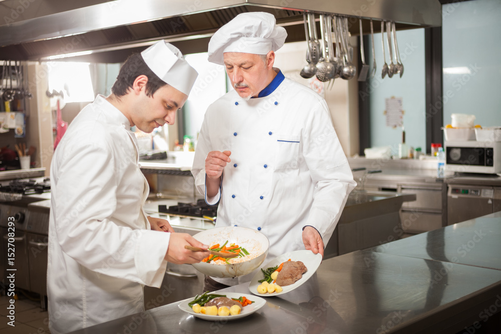 Chefs preparing a dish in a kitchen Chefs preparing a dish in a kitchen