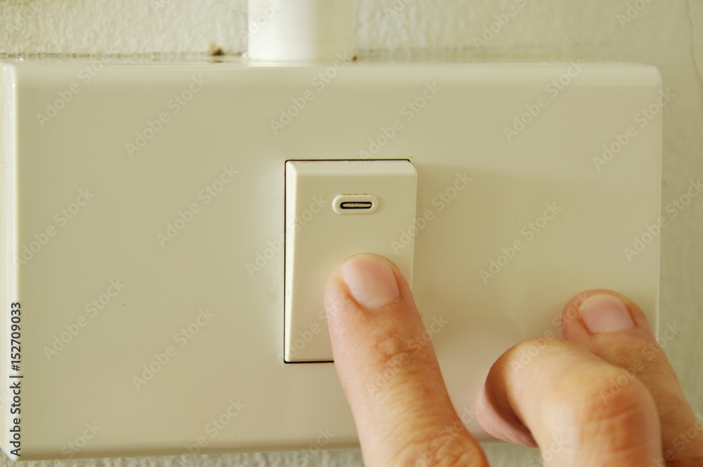 human finger closed toggle switch in plastic box on wall human finger closed toggle switch in plastic box on wall