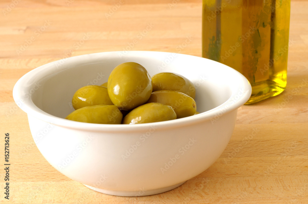 Green olives and extra virgin olive oil on the kitchen table, close up Green olives and extra virgin olive oil on the kitchen table, close up