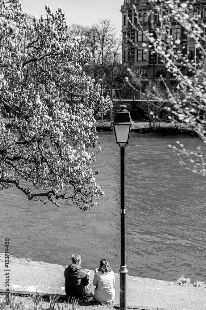 Fototapeta premium Pair sitting near the river, spring day