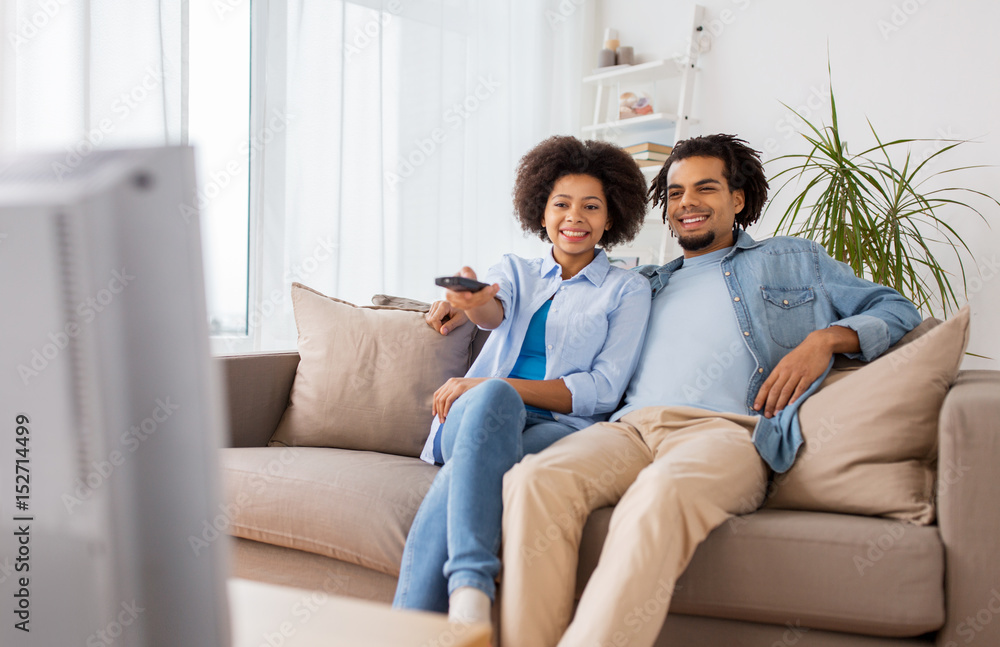 smiling couple with remote watching tv at home smiling couple with remote watching tv at home