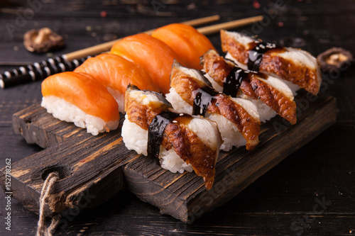 Eel sushi and salmon nigiri on wooden cutting board
