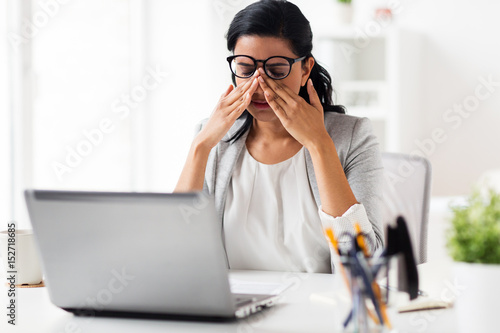 businesswoman rubbing tired eyes at office