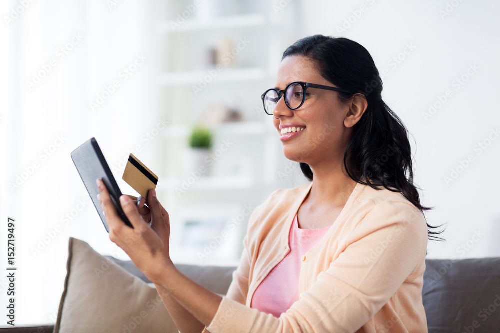 happy woman with tablet pc and credit card at home