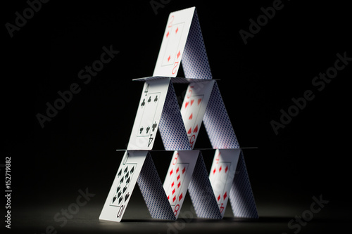 house of playing cards over black background