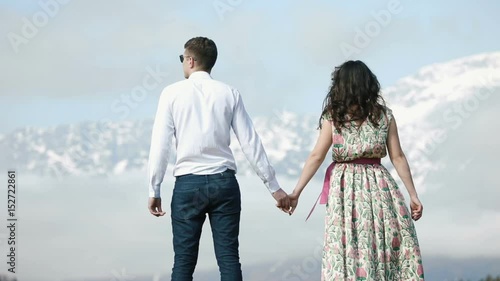 The back view of the couple holding hands and enjoying the skyscape. photo