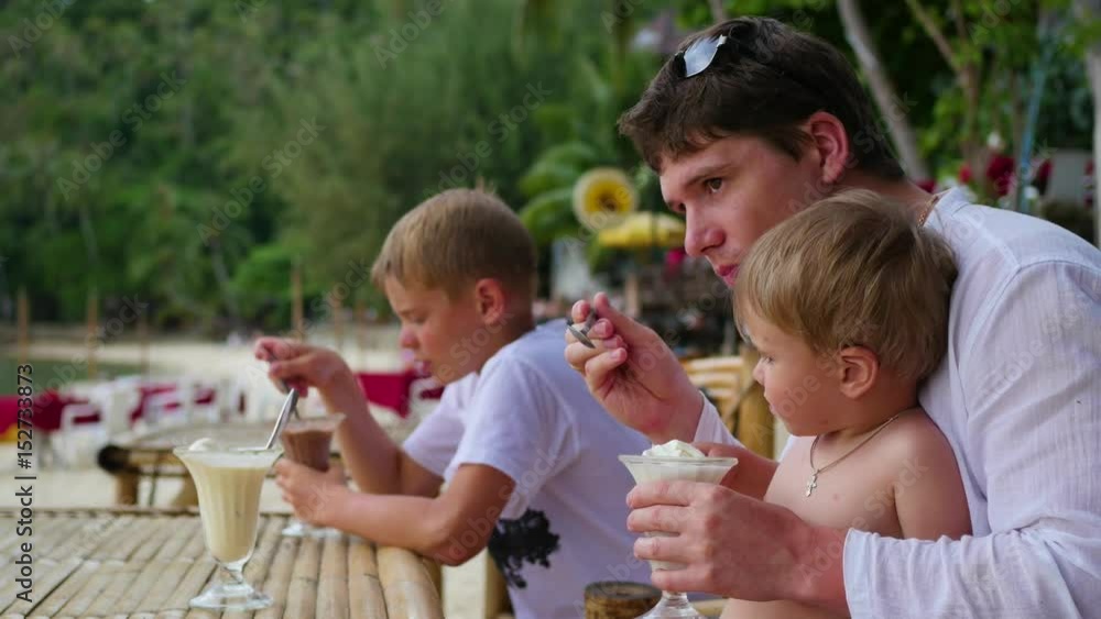 The family eats ice cream in a cafe on the beach The family eats ice cream in a cafe on the beach