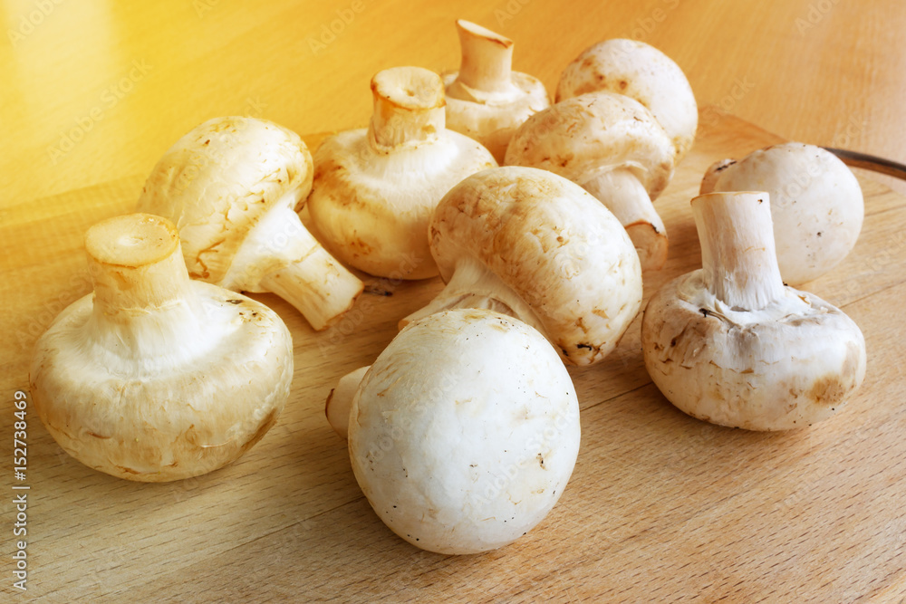 Champignons on a wooden cutting board in the sunlight Champignons on a wooden cutting board in the sunlight