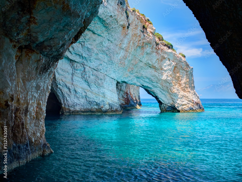 Blue caves rock arces arches of Blue caves from sightseeing boat with tourists in blue water of Ionian Sea inside cave, Island Zakynthos, Greece holidays vacation tour. Trip from Agios Nikolaos port