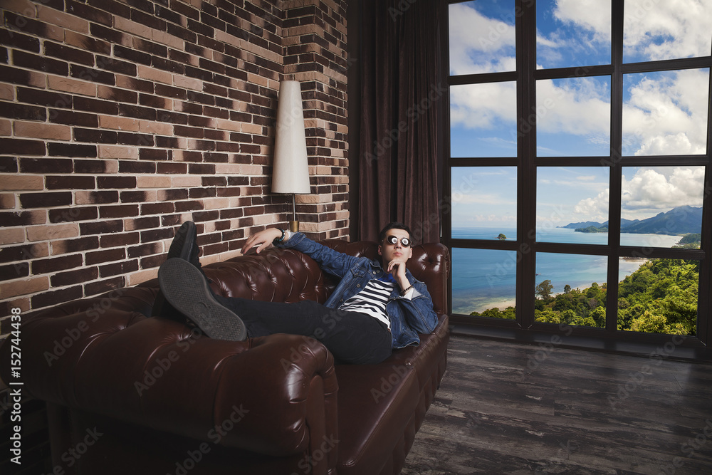Obraz premium The man is lying on the couch in the room overlooking the sea