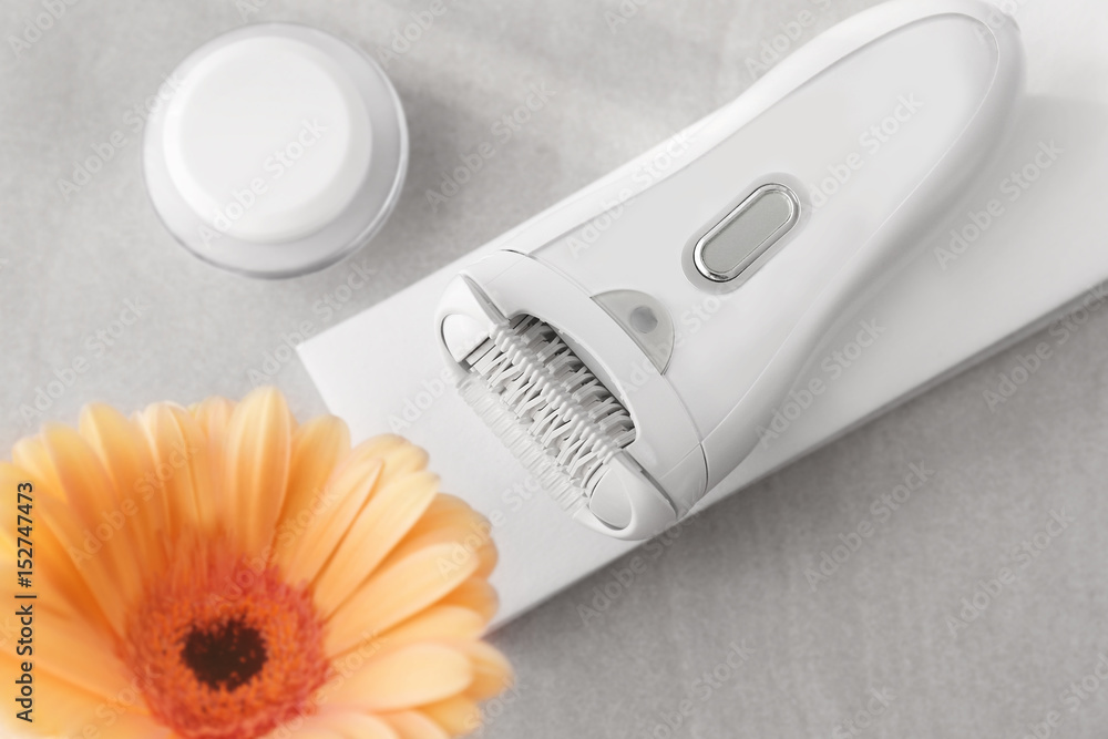 Modern epilator, wax strips and jars with cream on light background Modern epilator, wax strips and jars with cream on light background