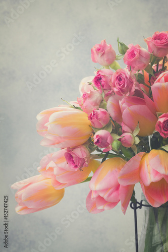 Fototapeta Naklejka Na Ścianę i Meble -  fresh pink and yellow tulips and roses close up on gray background, retro toned