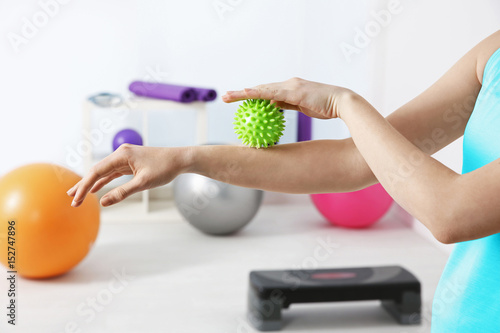 Hands of woman doing exercises with rubber ball in clinic