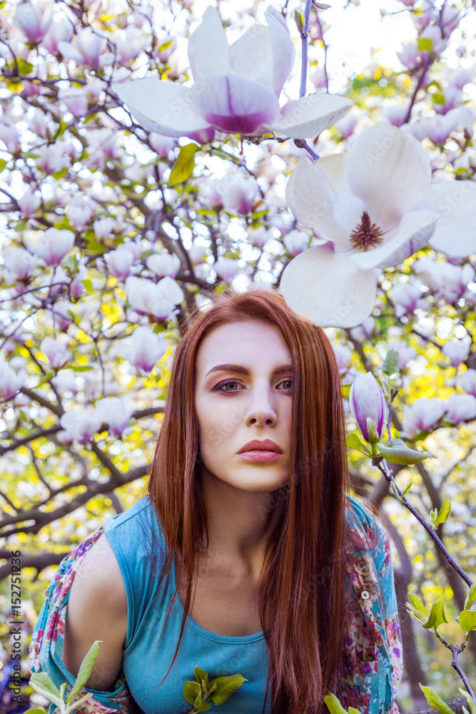Portrait of young beautiful woman posing among blooming trees with pink eyeshadow. Spring look on magnolias background. looking at camera. Portrait of young beautiful woman posing among blooming trees with pink eyeshadow. Spring look on magnolias background. looking at camera.