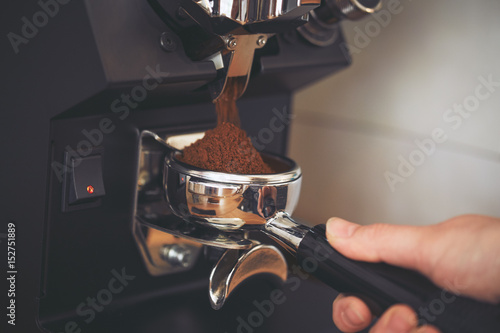 Fotografia, Obraz Coffee grinder grinds freshly coffee beans in a portafilter