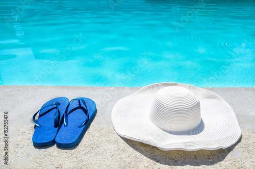 Summer hat and flip flops near the pool