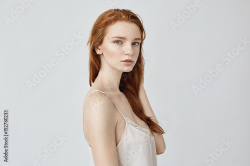 Tender redhead girl posing in profile looking at camera.