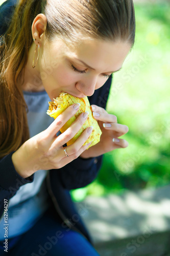 The girl eats shawarma on the street