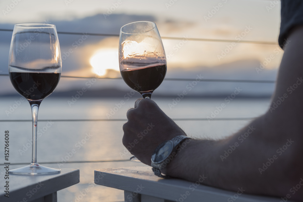 Romantic wine close up couple sitting at sunset on deck drinking