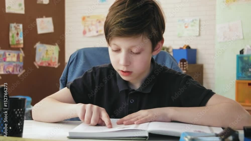 Cute little boy reading a book for school in his room Cute little boy reading a book for school in his room