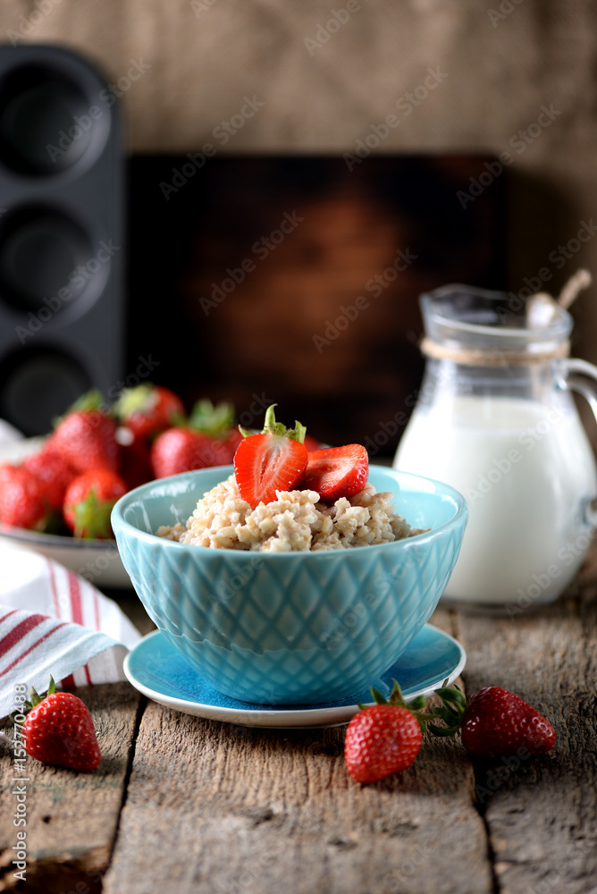 Oatmeal with fresh strawberries and milk on an old wooden background. Healthy breakfast. Healthy food. Oatmeal with fresh strawberries and milk on an old wooden background. Healthy breakfast. Healthy food.
