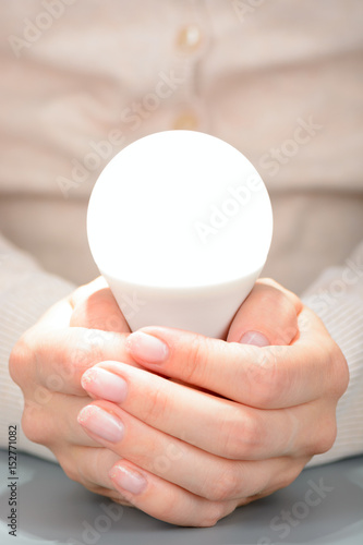 Female hands holding a glowing led bulb