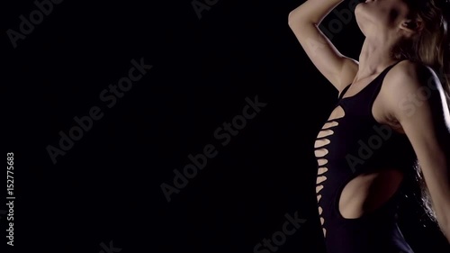 Slender girl model smoothly moves the entire body in a dark room. Wearing sexy comfortable clothes. photo