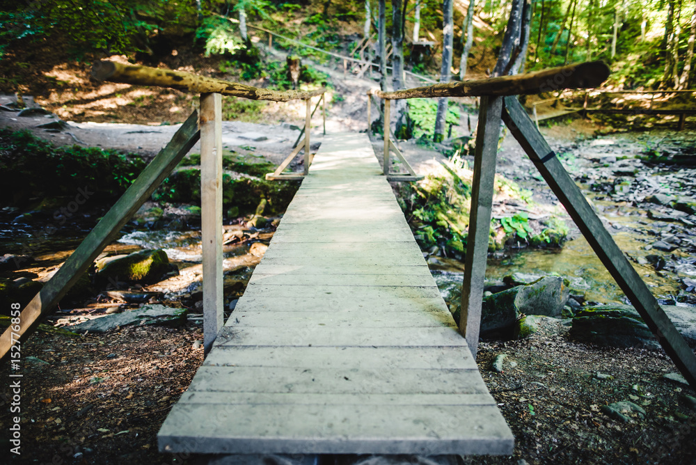 Obraz premium Wooden bridge over a small river in the forest