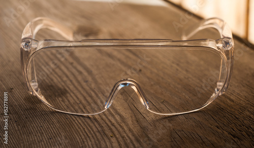 protective transparent plastic glasses on a wooden backgroun photo