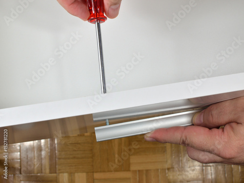 Man's hands screwing a handle in a drawer side 