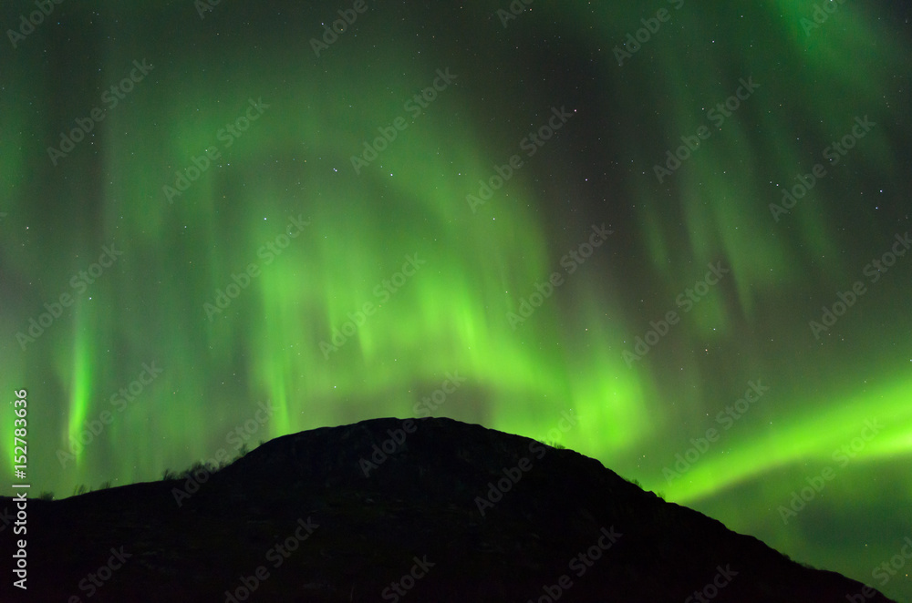 The Aurora in the sky above the hills at night . The Aurora in the sky above the hills at night .