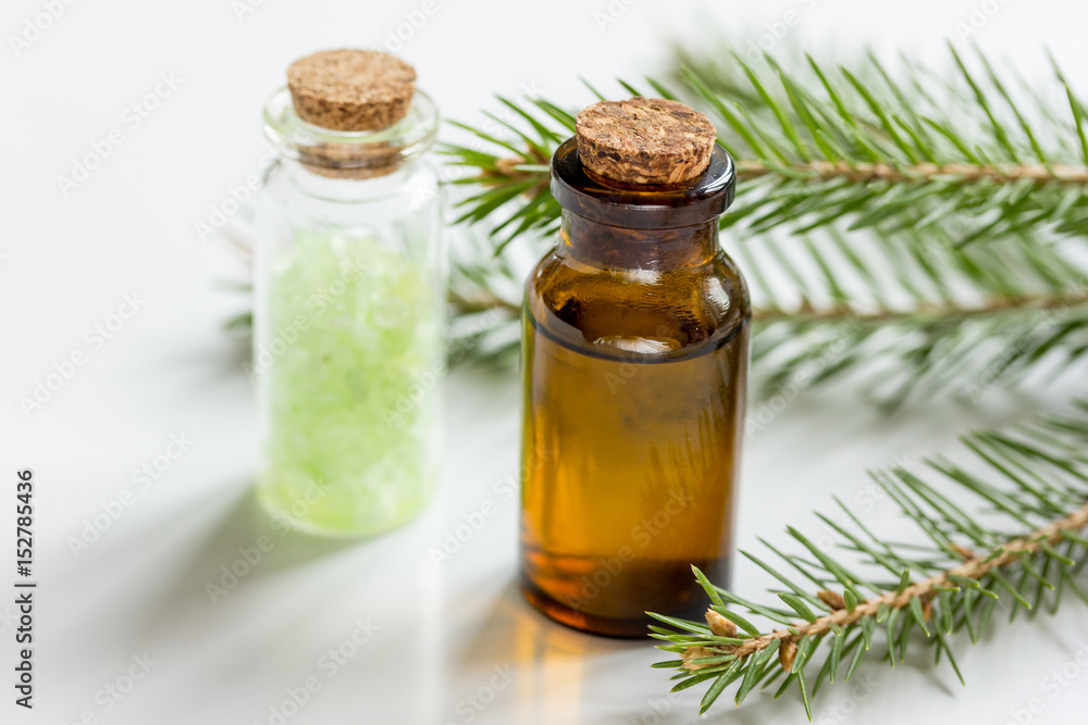 fir branches and spruce bath salt and aroma oil on white table background fir branches and spruce bath salt and aroma oil on white table background