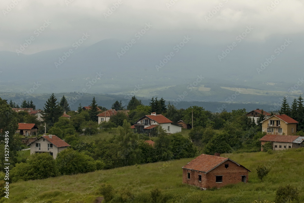 Scene with mountain glade, forest and residential district of bulgarian village Plana, Plana mountain, Bulgaria 