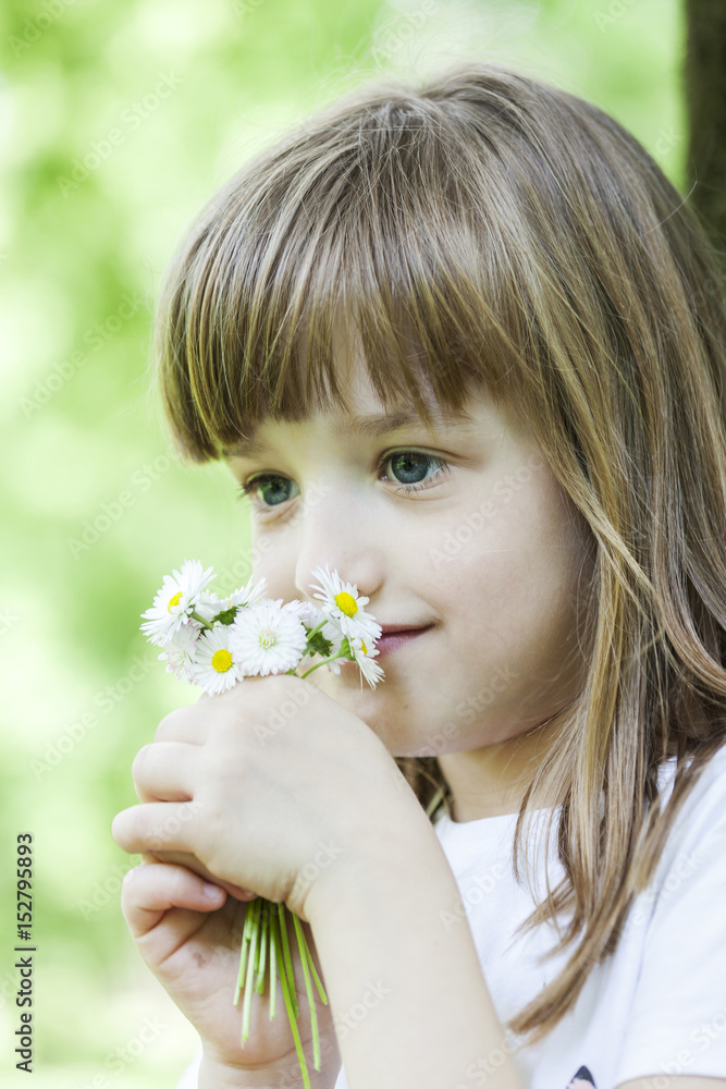 The little girl in the park smelling wildflowers The little girl in the park smelling wildflowers